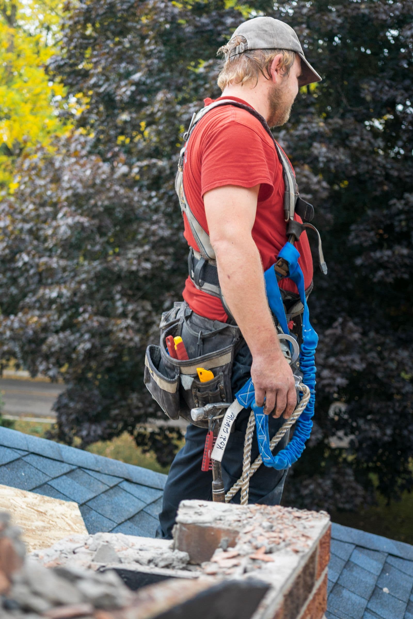 Roofing professional in fall protection inspecting a residential roof